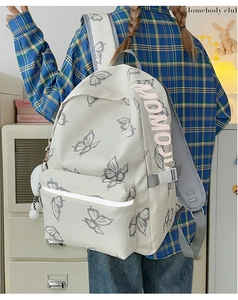 Detailed view of white canvas backpack with butterfly print and pink MOMO lettering