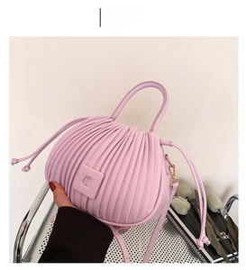 Detailed view of pink pleated PU leather handbag featuring vertical folds and round handle