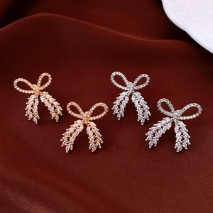 Detailed view of bow earrings with cubic zirconia in gold and silver on red velvet