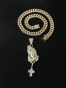 Close-up of hip hop golden Cuban chain and praying hands cross pendant with shiny diamonds
