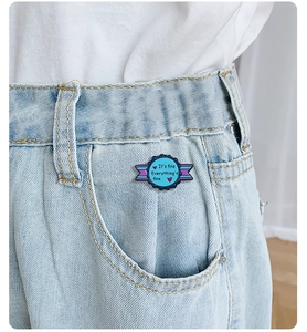 Detail of round enamel badge pin with ribbon design on denim pocket