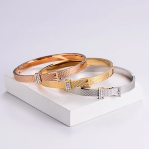 Belt buckle style metal bracelets with grid texture and cubic zirconia on white stands