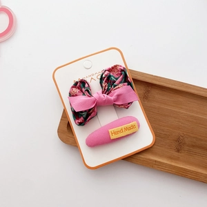 Detail of floral bow hair clip and pink handmade snap clip set on a display card