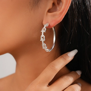 Macro view of silver U-shaped horsebit earrings with sparkling cubic zirconia on model
