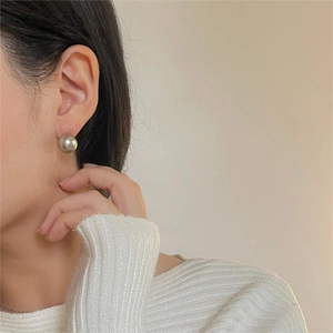 Close-up of silver-grey round pearl stud earrings worn by a model in a minimal style