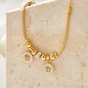 Gold tree of life bracelet with sparkling crystal accents on stone display stand
