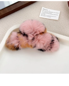 Detail of a large pink rabbit fur hair claw clip with brown leopard spots on a tray