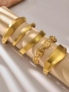 Detalle de cinco brazaletes irregulares de acero bañados en oro de 18k con acabado de espejo