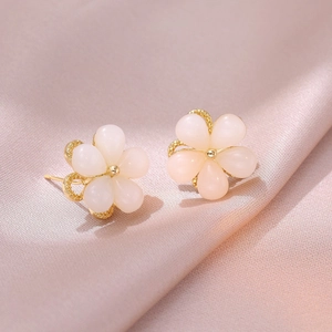 Elegant flower stud earrings with pink petals and gold center on soft pink silk fabric