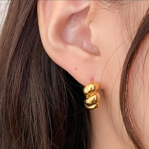 Close-up of triple-layered twisted gold hoop earrings worn for a vintage elegant look