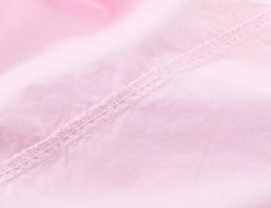 Detailed close-up of fine stitching and light pink cotton poplin fabric texture on shirt