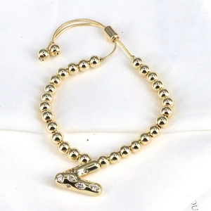 Detail of golden beaded bracelet featuring a sparkling zircon initial V pendant with drawcord