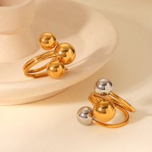 Detail of two-tone and gold geometric rings featuring polished metallic spheres