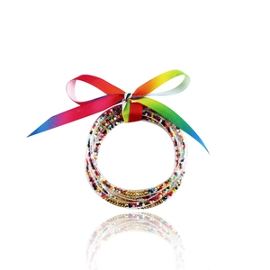 Dettaglio di bracciali a tubo glitterati con chiusura dorata e fiocco arcobaleno
