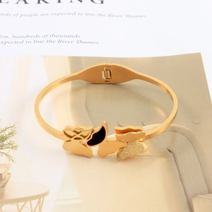 Close-up of golden butterfly bangle with matte texture and black center detailing