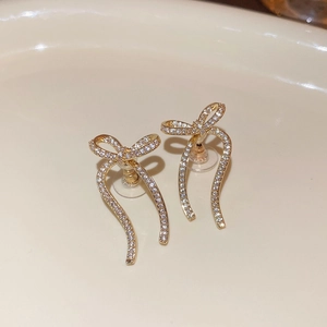 Macro shot of gold-plated bow earrings with pavé rhinestones and secure clear backs