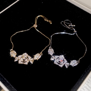 Macro view of gold and silver rose charm bracelets with sparkling crystals on velvet