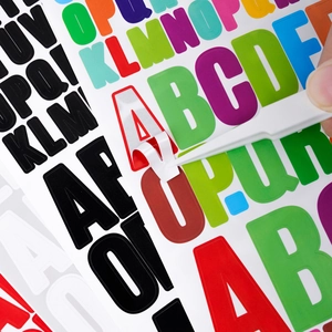 Close-up of peeling a red alphabet sticker with a tool for scrapbook decoration