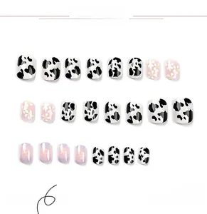 Detail of short square press-on nails with cow print, purple flowers and daisy designs