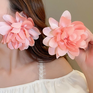 Close-up of model wearing oversized pink petal mesh earrings for beach vacation style