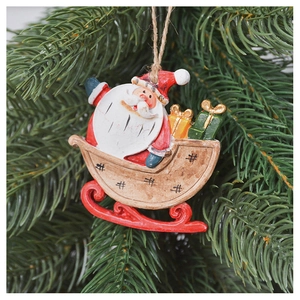 Detail of a Santa sleigh ornament with gift boxes hanging on a green Christmas tree branch