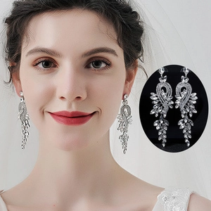 Close-up of sparkling silver tassel earrings with wing design and brilliant rhinestones