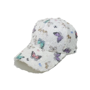 Close-up of white baseball cap with colorful butterfly print and tassel texture fabric