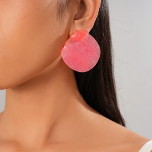 Detail of pink resin hoop earrings with textured finish worn by a model
