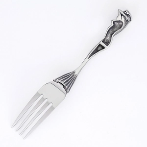Macro shot of stainless steel fork featuring a mermaid shaped handle in vintage style
