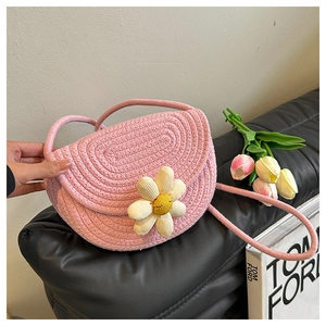 Detail of pink woven saddle bag featuring a white daisy flower with a smiley face