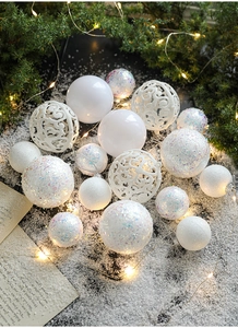 White Christmas ornaments set with glitter and hollow patterns on faux snow with lights
