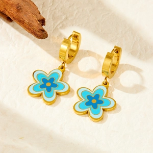 Boucles d'oreilles fleur bleue en acier inoxydable sur un fond beige texturé