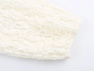 Detail of white textured lace sleeve cuff with delicate smocked fabric and elastic finish