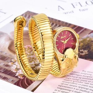 Detail of luxury gold snake-shaped watch with red quilted dial and diamond accents