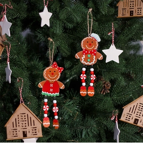 Detailed view of gingerbread man and wooden house ornaments hanging on a green Christmas tree