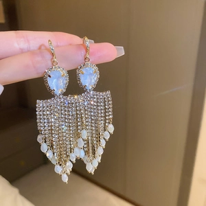 Macro shot of tassel earrings featuring blue drop gems, rhinestones and white pearls