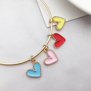 Macro view of a gold bracelet featuring four colorful enamel heart pendants on a white fabric