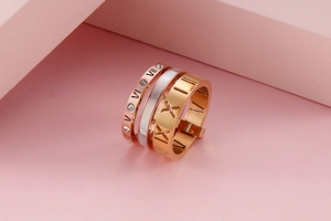 Close-up of stacked three-tone Roman numeral rings with crystal inlay on modern props