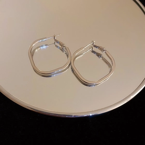 Close-up of geometric square earrings on a reflective mirror base with black backdrop
