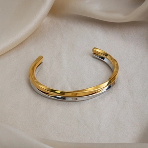 Detail of two-tone twisted open bangle with 18K gold and silver mirror finish on silk