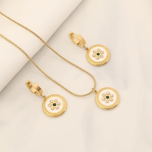 Golden necklace and earring set with white enamel floral charms and green gemstone centers