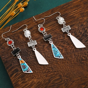 Detailed macro view of Bohemian floral drop earrings with turquoise beads on wood