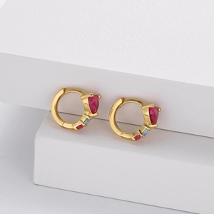 Macro shot of gold-plated S925 silver heart ruby earrings on white geometric stands