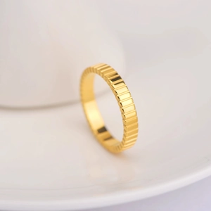 Macro detail of polished 18k gold plated stainless steel ring with gear pattern texture