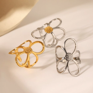 Detailed close-up of hollow flower rings in gold and silver steel finishes