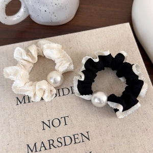 Close-up of black and white polka dot scrunchies with lace edges and large pearls