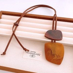 Close-up of geometric horn resin pendant necklace with brown faux suede cord