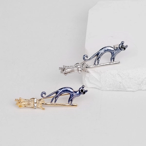 Broche chat volant sur balai en émail bleu et cristaux en finitions or et argent
