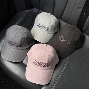 Close-up of four baseball caps with Zero Garage embroidery on a car seat background