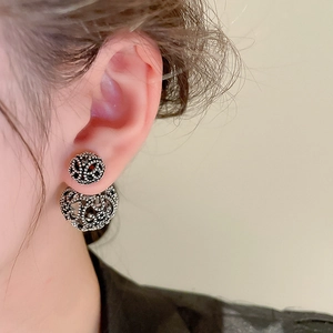 Close-up of vintage hollow silver sphere earrings with intricate floral patterns